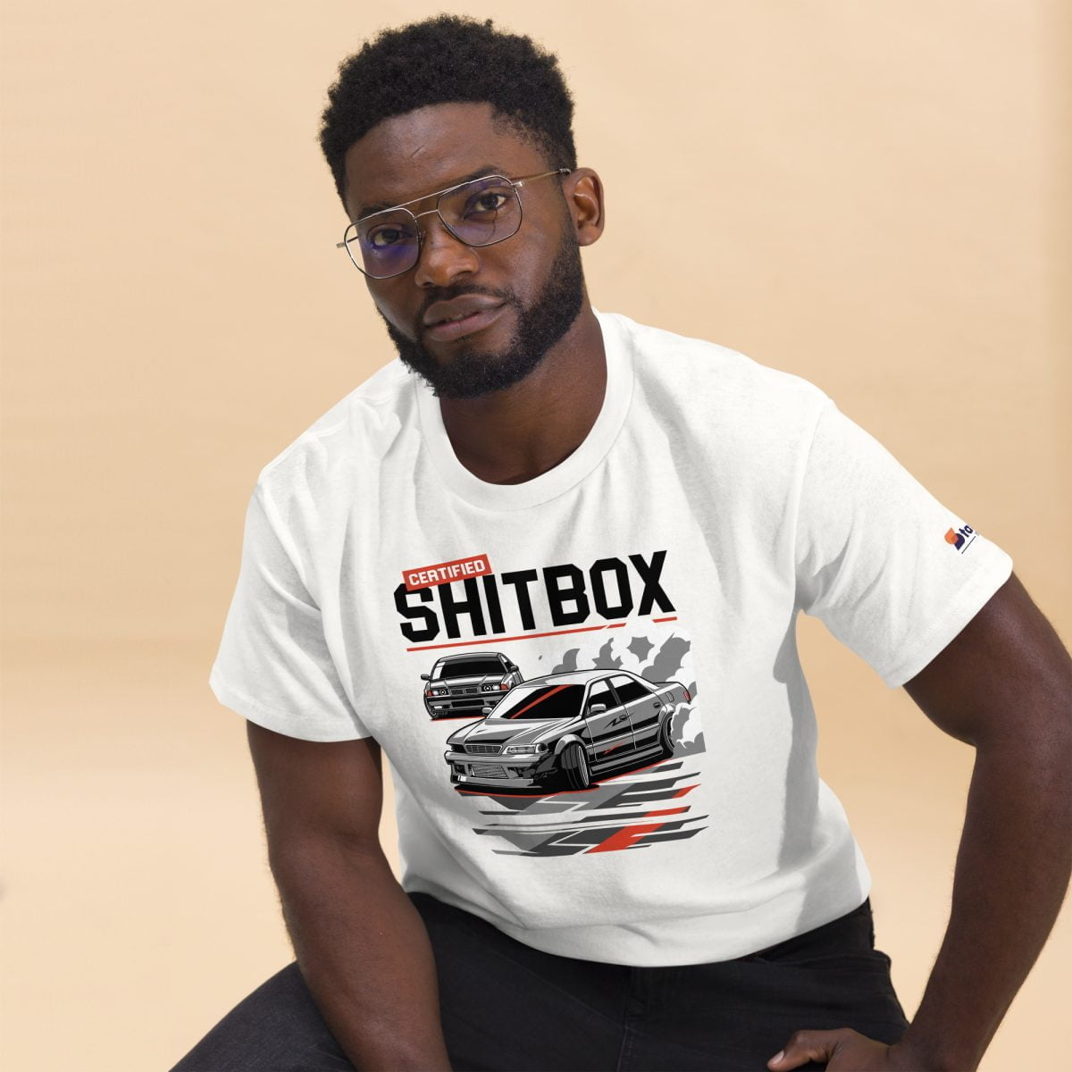 A man wearing a white t shirt with the product name E36 BMW JDM JZX100 Toyota Chaser Drifting Mens T shirt Certified Shitbox printed boldly showcasing his love for drifting and JDM cars | StancedLife