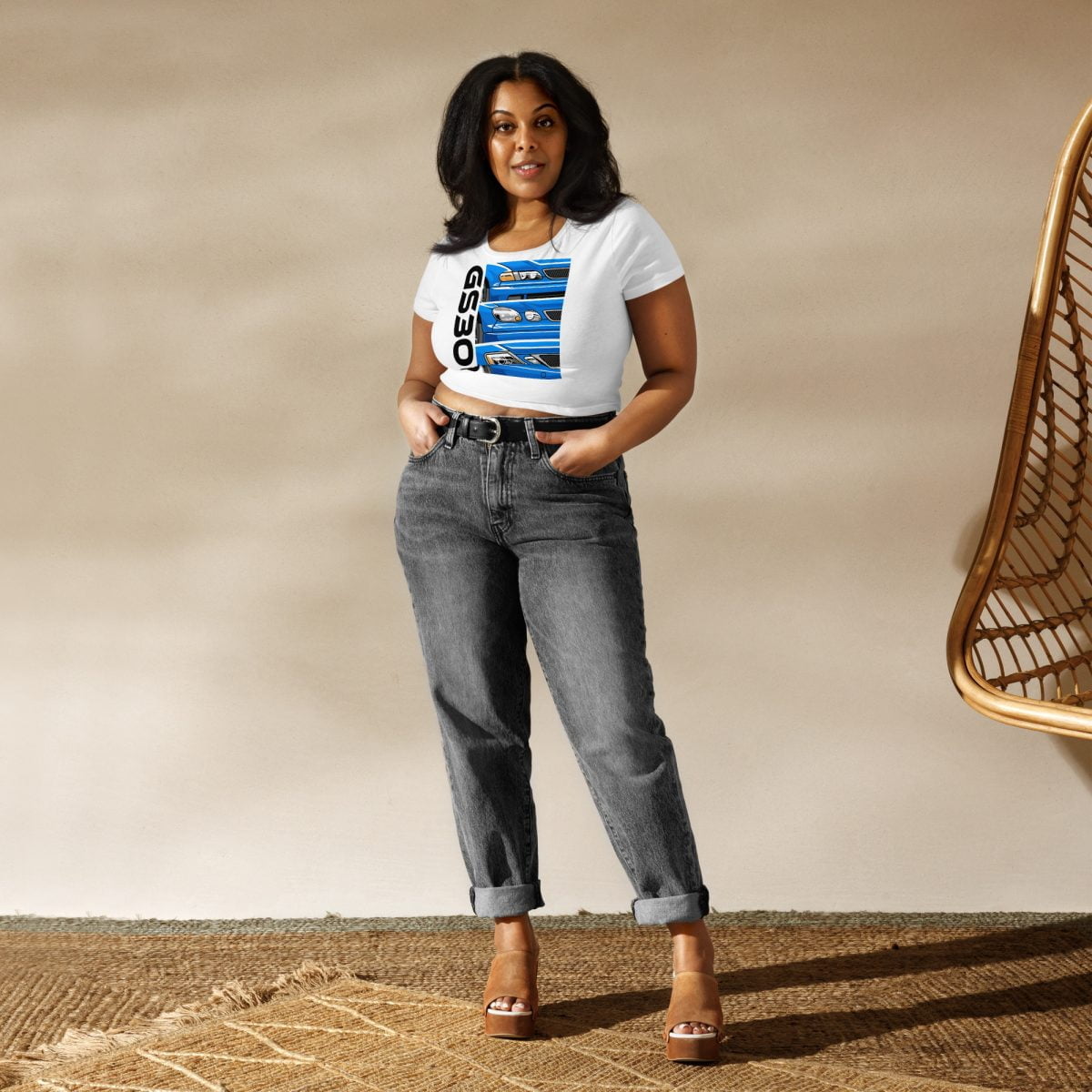 A woman wearing jeans and a t - shirt standing in front of a rug showcasing a Lexus GS300 JZS161 Generations Women’s Crop Tee.